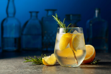 Cocktail gin tonic with ice, rosemary, and lemon.
