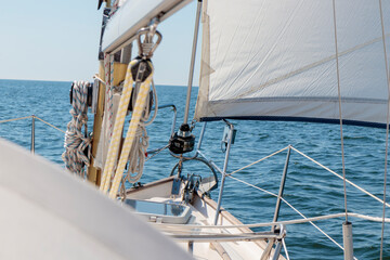 Obraz premium Luxury cruise on a sailing rigged yacht under a genoa sailing in a light wind during the regatta. Yachting as a luxury sport and great vacation. View from the deck to the bow, mast, sails.
