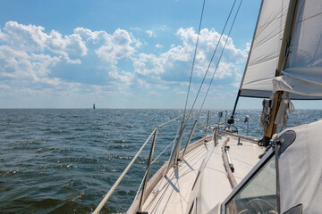 Luxury cruise on a sailing rigged yacht under a genoa sailing in a light wind during the regatta. Yachting as a luxury sport and great vacation. View from the deck to the bow, mast, sails.