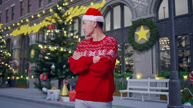 Offended Asian Man In Santa Suit Crossing His Arms And Looking Around While Standing In Christmas Night