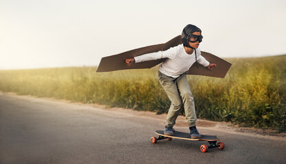 Skateboard, wings and child flying outdoor on road for airplane game, sport and holiday. Pilot,...