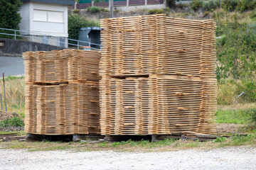 Large stacks of neatly arranged wooden boards are stacked outdoors on a bright, sunny day, likely...