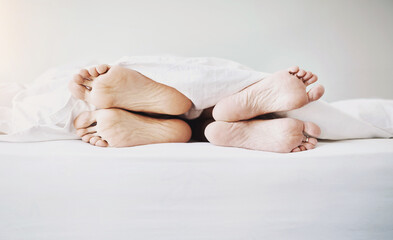 Feet, couple and bed in a home at morning with sleeping, rest and nap of people in bedroom. Legs, together and linen sheet with fight and face away from partner after divorce problem and issue