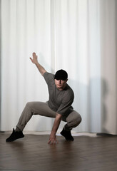 Fototapeta premium Dance in motion, pose of a man in hip-hop style clothes. Sports dancing guy in training poses. Dance training at home.