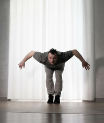 Fototapeta premium Dance in motion, pose of a man in hip-hop style clothes. Sports dancing guy in training poses. Dance training at home.