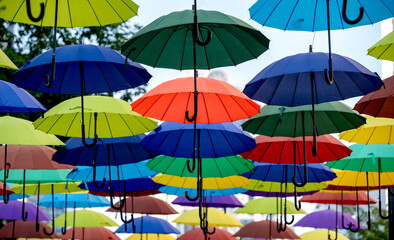 many colorful umbrellas fly and hover on the city street