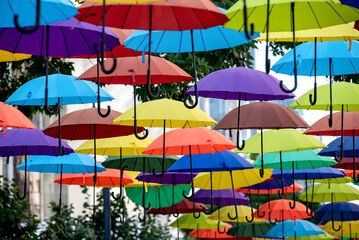 many colorful umbrellas fly and hover on the city street