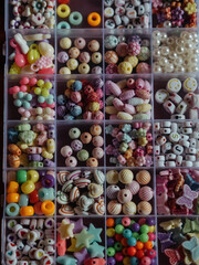 Kids Bead Set: A vertical, straight-from-above close-up shot captures beads in a plastic box, divided into sections based on their shapes, colors, and forms.