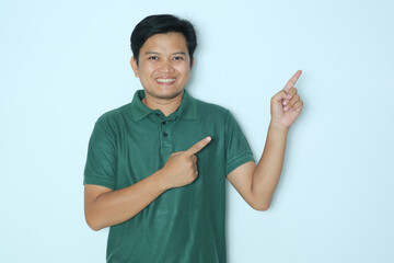 Young Asian man pointing to the left side with excited expression. Wearing a green a shirt