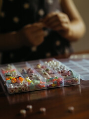 Kid Craft with Beads: A vertical close-up shot captures an open box of beads in focus, with the blurred backdrop of a toddler's hands creating bead jewelry.