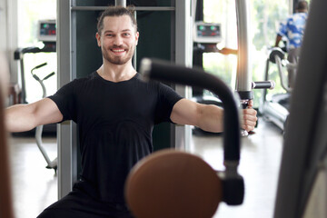 Strong muscular man exercising with sport equipment at gym. Sport man using chest press machine for exercise at fitness. Athletic workout training bodybuilding program for healthy and perfect body.