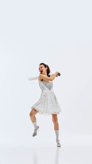 Elegant woman in polka dot dress and vintage shoes carrying giant cardboard tube. Classic 1950s style. Woman showing her powerful emotions and readiness for victory. Concept of lifestyle and business