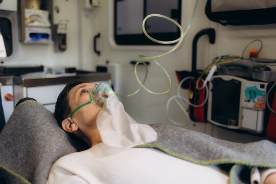 Ambulance interior with male paramedic measuring pulse on senior woman