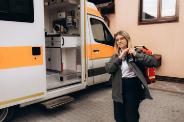 attractive young female emergency medical service worker in front of ambulance