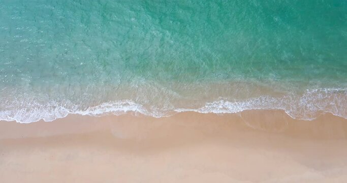 Aerial view drone shot Top-view of beach and sea, Seawater wave on sandy beach. Beach on the tropical island. (4K DCI 4096x2160p 10bit 4:2:2)