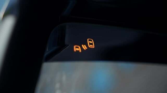 Close up turning on the blind spot warning BSW system on the side mirror of a car in a city traffic jam.
