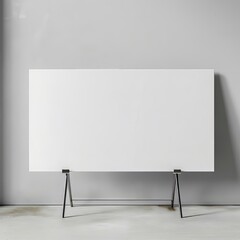 Blank canvas on metal easel stands in front of a concrete wall