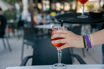 Waitress holding spritz cocktail serving restaurant customer. Waitress is serving a refreshing spritz cocktail on a tray to a customer in a restaurant