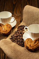 Coffee cups, cookies and coffee beans on the wooden background.