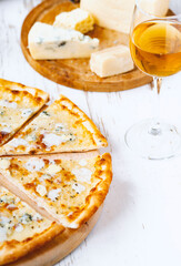 Pizza quattro formaggi on a wooden board .four cheese pizza and fresh ingredients for a four cheeses Italian pizza on a white wooden desk .