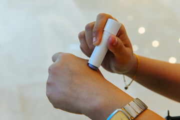 close up view of a woman's hand applying lip balm on the skin of the hand to check allergies