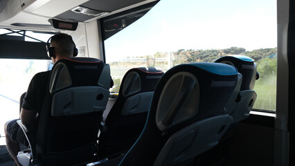 Traveler on a bus. Passenger traveling on public transportation. Young man in bus listening to music with headphones.