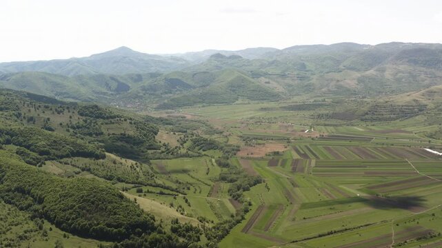 Slow aerial panning view over fertile valley farmland near Piatra Secuiului, villages of Rimetea and Coltesti, Romania