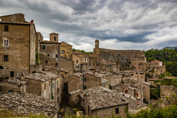 Fototapeta premium A glimpse of the ancient medieval village of Sorano, on a melancholy and rainy spring day. In the province of Grosseto, Tuscany, Italy. The old houses built in stone and tuff bricks.