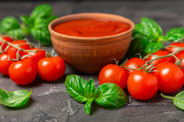 Fresh cherry tomatoes and fresh green basil on a textured background. Tomato sauce. Vegan. Ingredients for salad. Organic food. Place for text. Copy space.