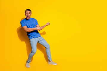 Full length photo of handsome young guy pull empty space dressed stylish blue garment isolated on yellow color background