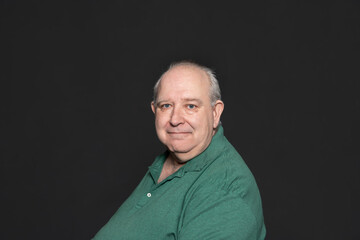 Overweight sexagenarian man with white hair and blue eyes, dressed in a green polo shirt, looking...