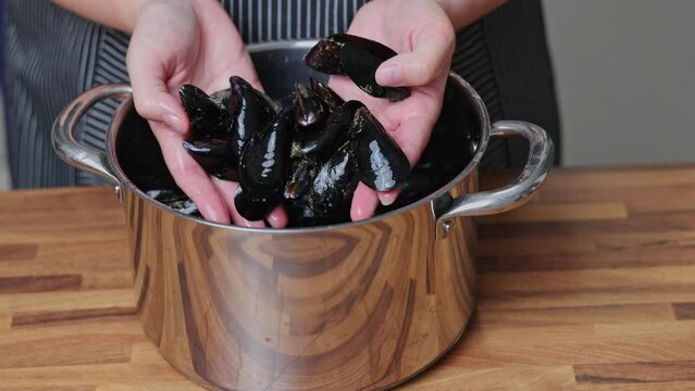A woman cleans mussels in a domestic kitchen