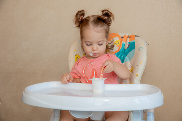 A little girl is sitting on a high chair eating at home