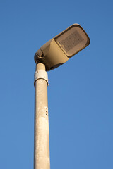 A single streetlight stands tall against a pristine, cloudless blue sky, bathing in daylight, capturing the simplicity and functionality of urban infrastructure.