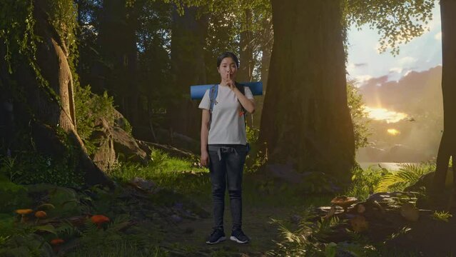 Full Body Of Asian Female Hiker With Mountaineering Backpack Looking At Camera And Making Shh Gesture While Exploring Forest Nature