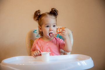 A little girl is sitting on a high chair eating at home