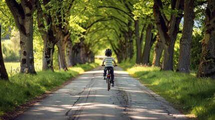 Fototapeta premium Happy child cycling on tree-lined path with space for text and wearing safety helmet and enjoying outdoors adventure
