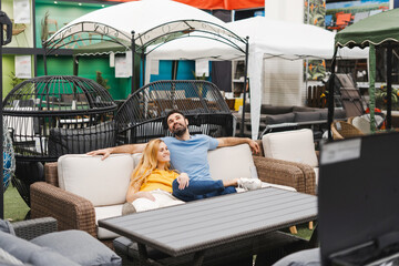 Happy young couple sitting on the sofa for terrace in the furniture department of store