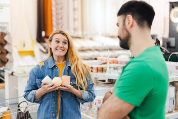 Smiling woman holding decorative candles looking at her boyfriend in a store in the decor department