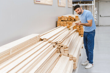 Man in a construction supermarket choosing plywood and boards for construction