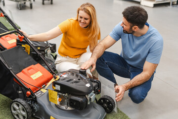 Happy young family choosing lawn mower while coming to the garden tools store