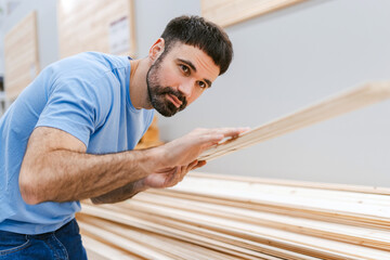 Fototapeta premium Man in the lumber department choosing wood building materials for the renovation of his house