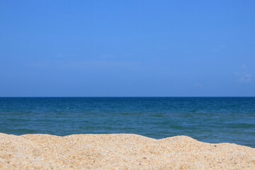 The sky and sea are bright blue, and the foreground is made up of multi-level sand dunes.