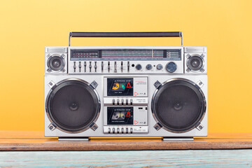 Retro boombox radio cassette recorder from 1980s front yellow background. Vintage old style...