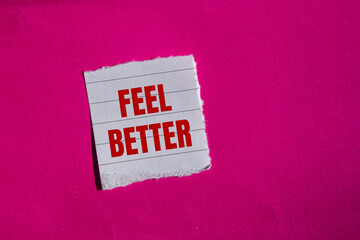 Feel better message written on ripped torn paper piece with pink background. Conceptual feel better symbol. Copy space.