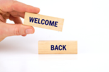 Life and business motivational inspirational concept. Welcome Back, text words on wooden blocks with a man's hand on a white background