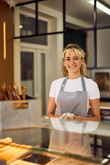 A lovely girl working at the bakery, smiling for the camera.