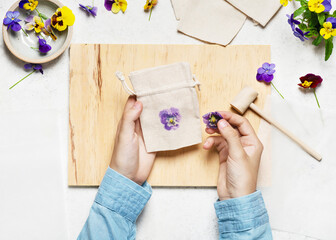 Step 4. Peel off the top layer of fabric to reveal the print and pull the flower off. Hammered Flower Prints on Fabric bag. Natural material craft for kids concept. Top view.