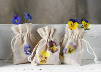Three small handmade fabric bags with beautiful hammered pansy flower prints on white kitchen...