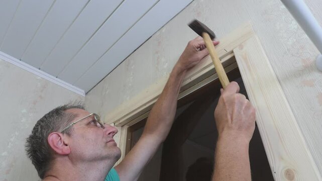 Casing of glass  door on sauna, Joiner trimming doorway jamb with nailing.